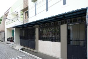 un edificio blanco con una puerta negra en una calle en RedDoorz Hostel near Kota Lama Semarang, en Semarang