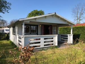 een klein wit huis met een wit hek bij Sfeervolle Blokhut in Oostvoorne