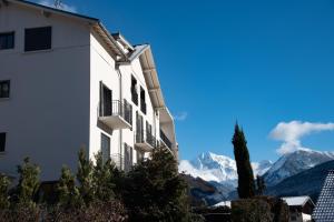 un edificio blanco con montañas en el fondo en Le Clos Caroline en Brides-les-Bains