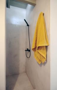 eine Dusche mit einem gelben Handtuch an der Wand in der Unterkunft New Guesthouse in Emporios in Emporeiós