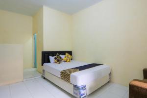 Schlafzimmer mit einem Bett mit gelben und blauen Kissen in der Unterkunft OYO 2371 Islami Family Residence in Blimbingsari