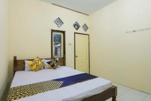 a bedroom with a bed with yellow and blue pillows at OYO 2371 Islami Family Residence in Blimbingsari