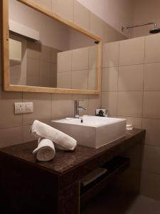 La salle de bains est pourvue d'un lavabo blanc et d'un miroir. dans l'établissement Résidence Riva Bella, à Port-Louis