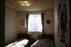 sypialnia z 2 łóżkami i oknem w obiekcie Pension Half Time w mieście Hokuto