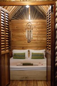 a bed in a room with a wooden wall at Palayan Paradise Huts in San Vicente
