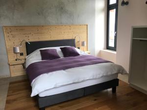 ein Schlafzimmer mit einem großen Bett mit lila und weißen Laken in der Unterkunft Le Manoir de l'Oselière & Spa in Les Hauts-Geneveys