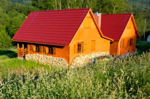 an orange house with a red roof in a field at Chatka w gorach in Lewin Kłodzki