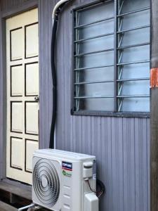 einem Ventilator neben einem Gebäude mit Fenster in der Unterkunft Z&Z Budget Room in Kampung Kuala Besut