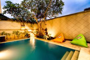 een zwembad met groene en oranje kussens naast een boom bij Villa Chandra - 3 Bedroom Villa with Private Pool in Seminyak
