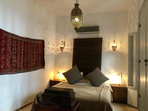 a bedroom with a bed with two night stands and lights at Riad Bellamane Marrakech in Marrakech +74 photos