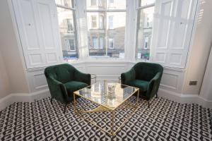 two green chairs and a glass table in a room at The Lane Hotel in Edinburgh