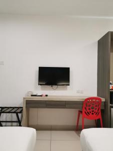 a room with a desk with a television and a red chair at Hotel Alpha in Bukit Mertajam