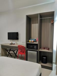 Schlafzimmer mit einem Schreibtisch, einem roten Stuhl und einem Bett in der Unterkunft Hotel Alpha in Bukit Mertajam
