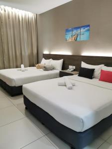 two beds in a hotel room with white and red pillows at Hotel Alpha in Bukit Mertajam