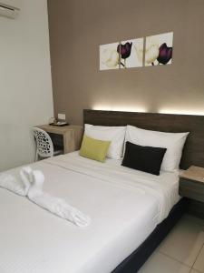 ein Schlafzimmer mit einem großen Bett mit weißer Bettwäsche und Kissen in der Unterkunft Hotel Alpha in Bukit Mertajam