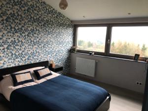 a bedroom with a large bed with a blue blanket at By Chris in Malmedy