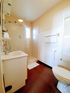 a white bathroom with a toilet and a sink at Le Toul' Broch in Baden