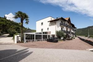 een wit gebouw met een auto ervoor geparkeerd bij Hotel Landgasthof Weingut Seeperle in Caldaro