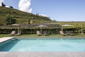 einen Pool mit Stühlen und Sonnenschirmen in der Unterkunft Hotel Landgasthof Weingut Seeperle in Kaltern