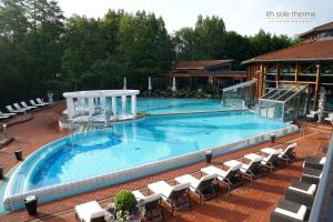 una gran piscina con sillas blancas en Waldhotel Humboldt, en Salzhemmendorf