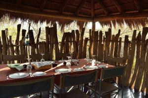 - une table en bois avec des chaises et des assiettes dans l'établissement Quatermain's 1920's Safari Camp – Amakhala Game Reserve, à Réserve animalière d'Amakhala