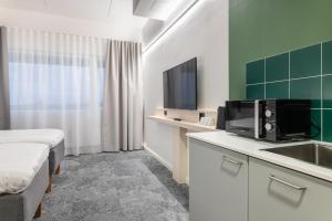 um quarto de hotel com uma cama e um lavatório e uma televisão em GreenStar Hotel Vaasa em Vaasa