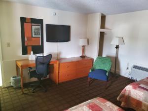 a hotel room with a desk and a tv and a bedroom at Relax Inn in Emporia