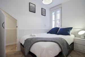biała sypialnia z łóżkiem z niebieskimi poduszkami w obiekcie LEEWAYS APARTMENT I in SAN LORENZO w Madrycie
