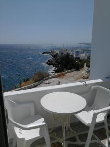 a white table and chairs on a balcony with the ocean at Vrohaki Studios & Rooms in Piso Livadi