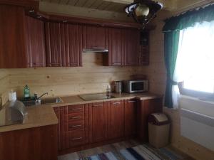 a kitchen with wooden cabinets and a sink and a microwave at Babiogórski Raj in Lipnica Wielka