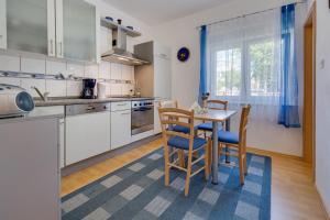een keuken met witte kasten en een tafel en stoelen bij Apartment Twisting By The Private Pool in Zadar