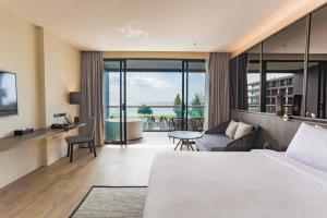 une chambre d'hôtel avec un lit et un salon dans l'établissement Ana Anan Resort & Villas Pattaya, à Na Jomtien