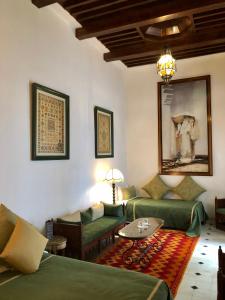 a living room with two green couches and a table at Riad Bellamane Marrakech in Marrakech