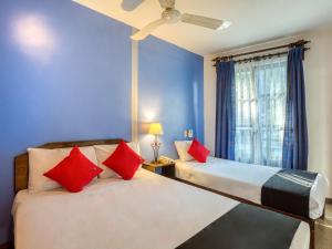 two beds in a room with blue walls and red pillows at Capital O Parador Crespo Hotel, Oaxaca in Oaxaca City