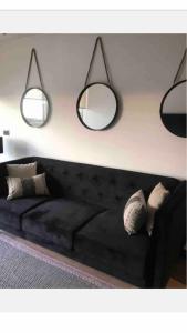 salon z czarną kanapą i 2 lustrami w obiekcie 80 Metros , costado Clinica las Condes ,hasta 5 personasn w mieście Santiago