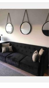 sala de estar con sofá negro y 2 espejos en Clínica Las Condes, espectacular departamento nuevo 80 m2, en Santiago