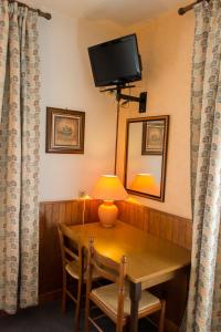 een kamer met een tafel met een lamp en een televisie bij Hôtel de Flandre in Compiègne