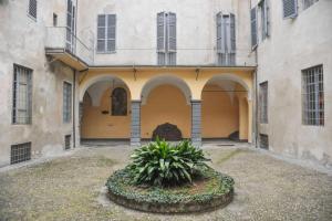 a building with a courtyard with a plant in front of it at Cozy apartment in Palazzo Malaspina in Piacenza