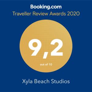 a sign that reads travel review awards with a yellow circle at Xyla Beach Studios in Melissaki