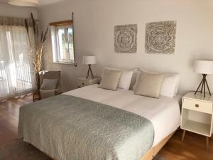 a bedroom with a large white bed and a chair at Casa Artelena in Chão de Parada