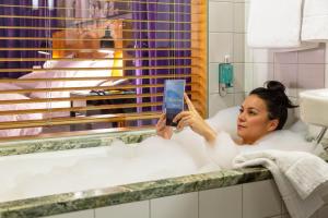 a woman sitting in a bath tub holding a cell phone at Hotel Rival in Stockholm