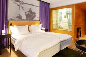 a bedroom with a large white bed with purple curtains at Hotel Rival in Stockholm