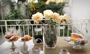 a table with a vase of flowers and cookies at Pompeii Ruins De Charme B&B in Pompei