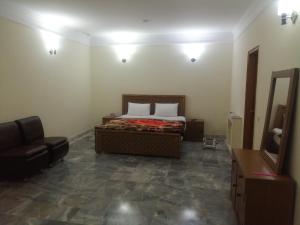 1 dormitorio con cama, silla y espejo en Star Hotel Lahore, en Lahore