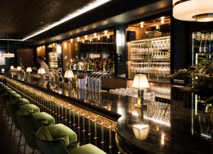 a bar with green chairs and a man in the background at Hotel Rival in Stockholm