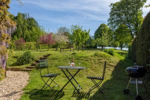 a table and chairs in a garden with a grill at Gardeners Cottage in Bridport