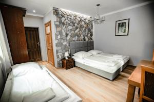 sypialnia z 2 łóżkami i kamienną ścianą w obiekcie Dom Nad Wodospadem w Międzygórzu