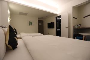 a bedroom with a large white bed and a table at Wountain Hotel in Hualien City