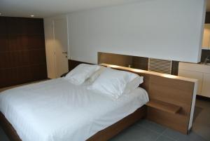 1 dormitorio con 1 cama grande con almohadas blancas en La Maison Contemporaine, en Namur