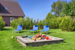 zwei blaue Stühle und ein Sandkasten im Hof mit Spielzeug in der Unterkunft Hof Lück in Esens